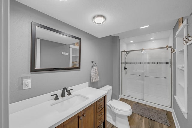 full bathroom featuring vanity, a stall shower, wood finished floors, and toilet