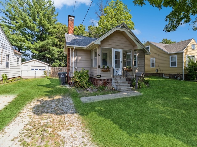 bungalow-style home with an outbuilding, a front yard, and a garage