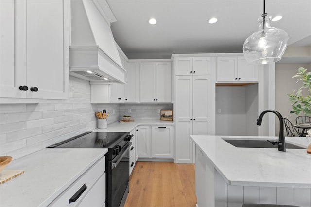 kitchen with black range with electric stovetop, custom range hood, sink, white cabinetry, and decorative light fixtures