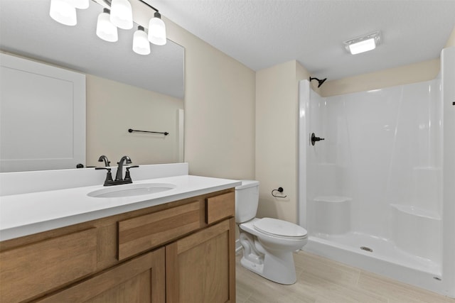 bathroom featuring toilet, walk in shower, a textured ceiling, and vanity