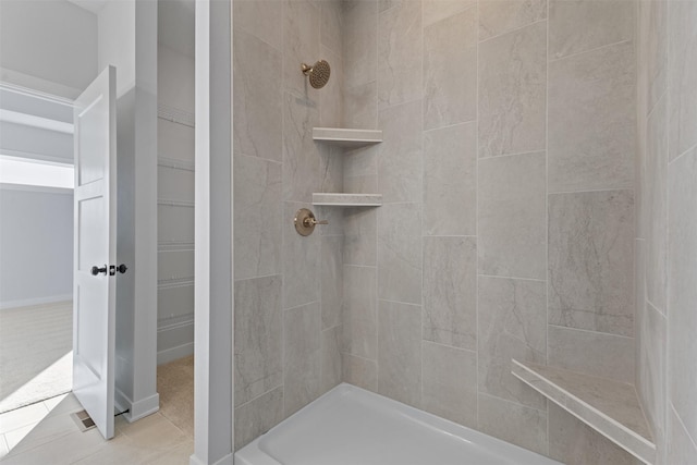 bathroom with a tile shower and tile patterned floors