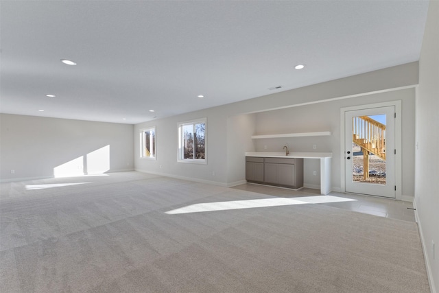 unfurnished living room with wet bar and light carpet