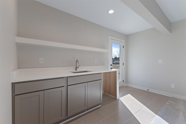 kitchen featuring sink, gray cabinetry, and beam ceiling