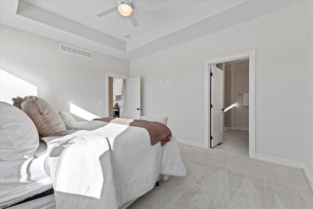 carpeted bedroom with a tray ceiling and ceiling fan