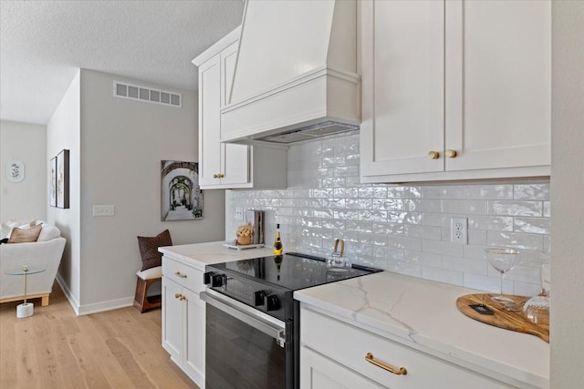 kitchen featuring white cabinets, electric range, light stone counters, light hardwood / wood-style floors, and custom range hood