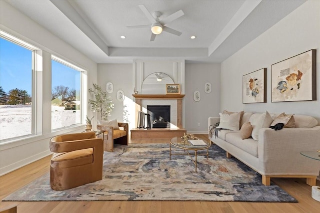 living room featuring hardwood / wood-style flooring, ceiling fan, and a tray ceiling