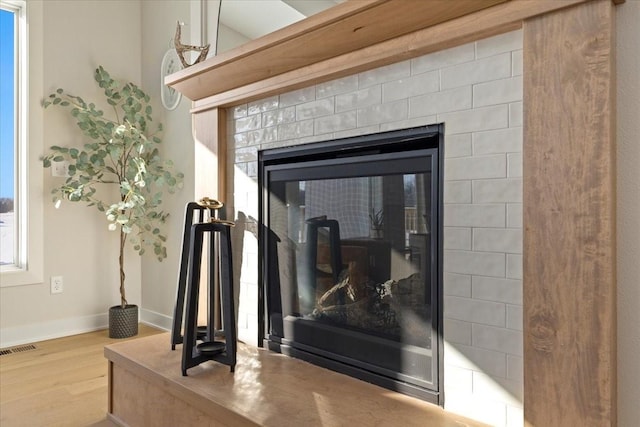 interior details featuring wood-type flooring and a tile fireplace