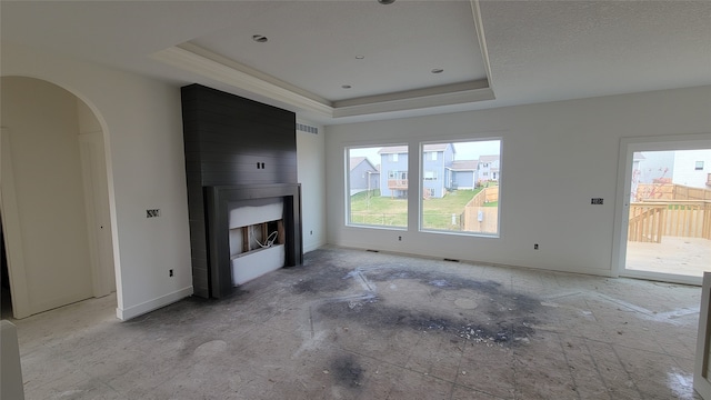 unfurnished living room featuring a wealth of natural light, a fireplace, and a tray ceiling