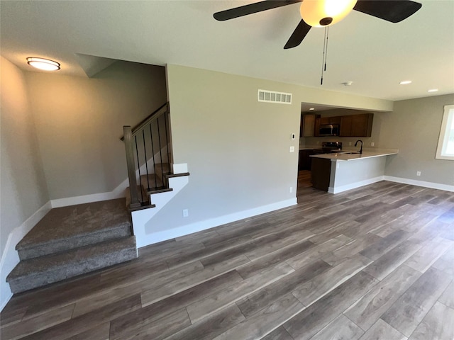 unfurnished living room with wood-type flooring, ceiling fan, and sink