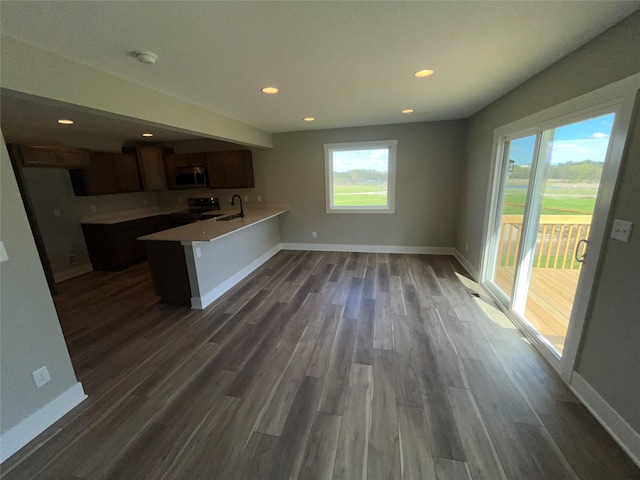 kitchen with sink, kitchen peninsula, dark wood-type flooring, and appliances with stainless steel finishes