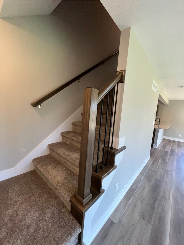 staircase with hardwood / wood-style floors and lofted ceiling