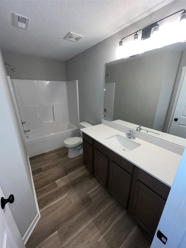 full bathroom featuring vanity, shower / washtub combination, hardwood / wood-style flooring, toilet, and a textured ceiling