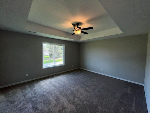 carpeted spare room with a raised ceiling and ceiling fan