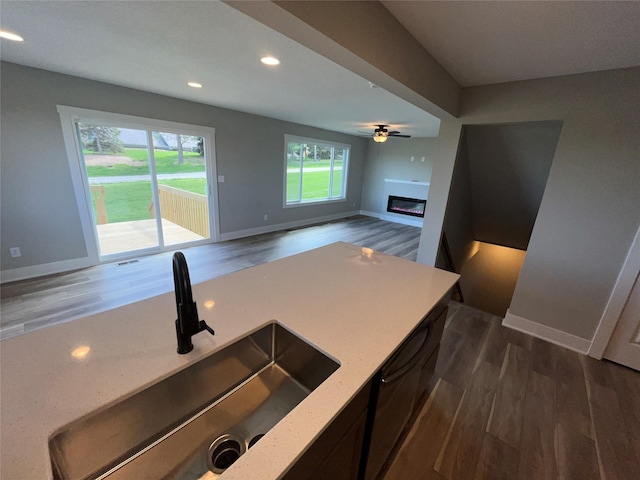 kitchen featuring ceiling fan, sink, dark wood-type flooring, and light stone counters