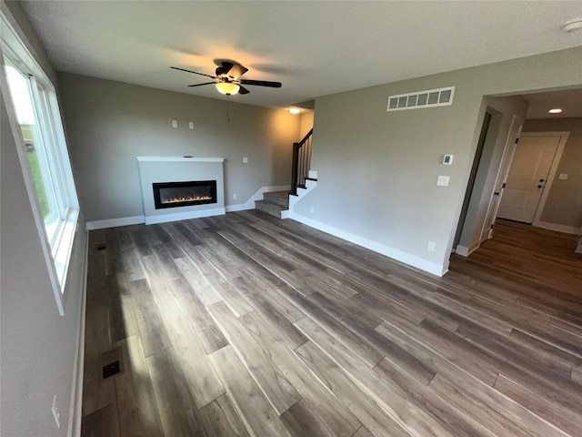 unfurnished living room with ceiling fan and dark wood-type flooring