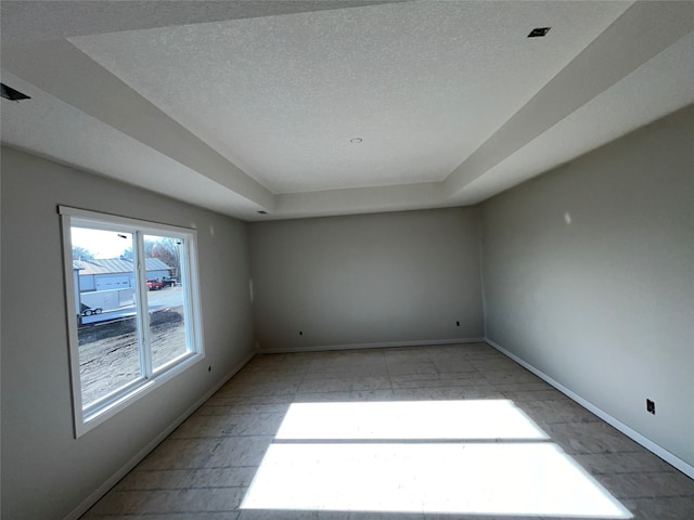 empty room with a textured ceiling and a tray ceiling