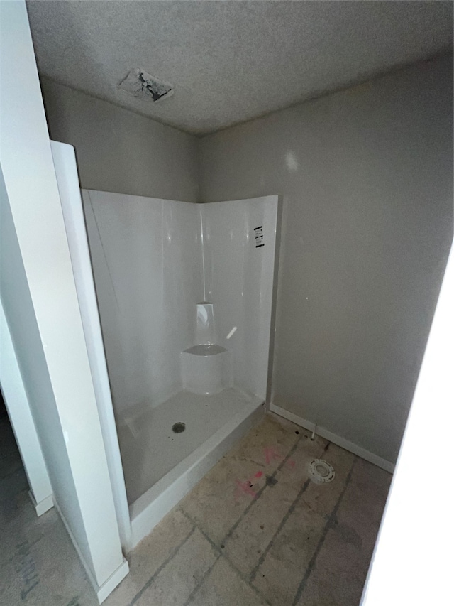 bathroom with a textured ceiling and walk in shower