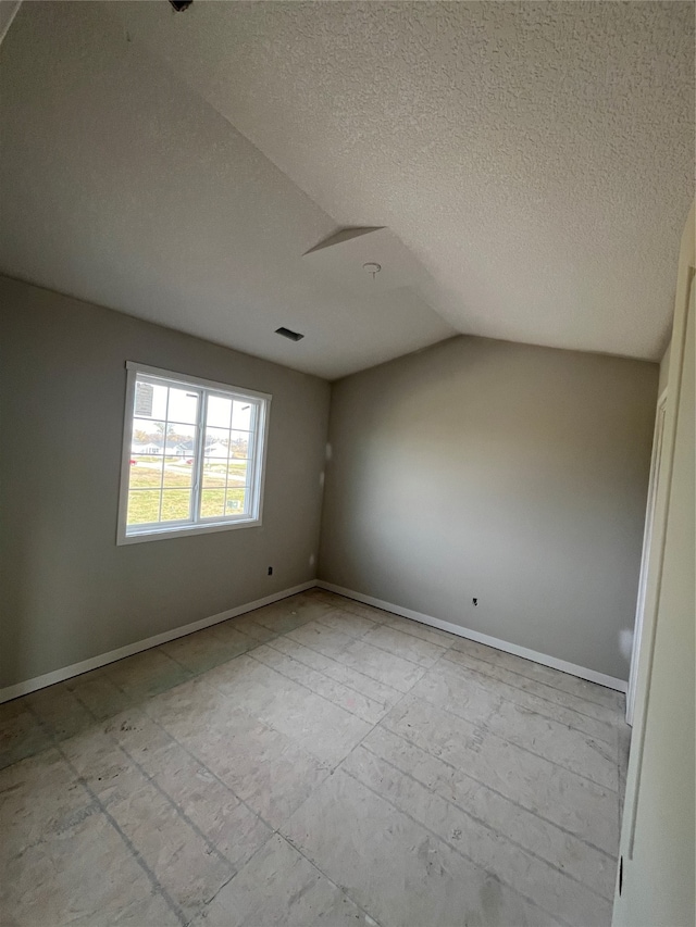 empty room with a textured ceiling and lofted ceiling