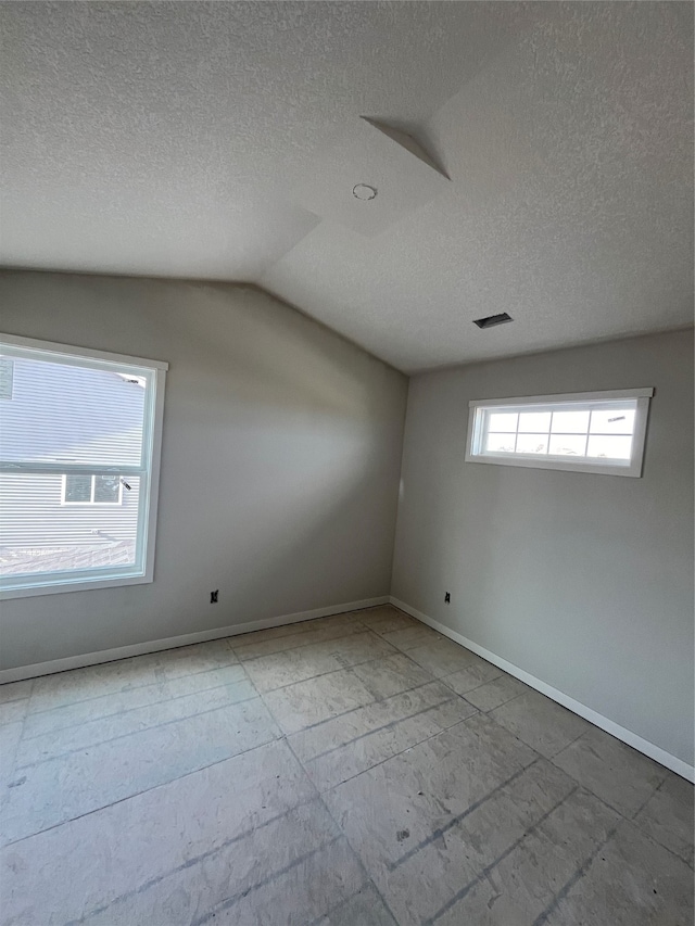 empty room featuring a textured ceiling and lofted ceiling