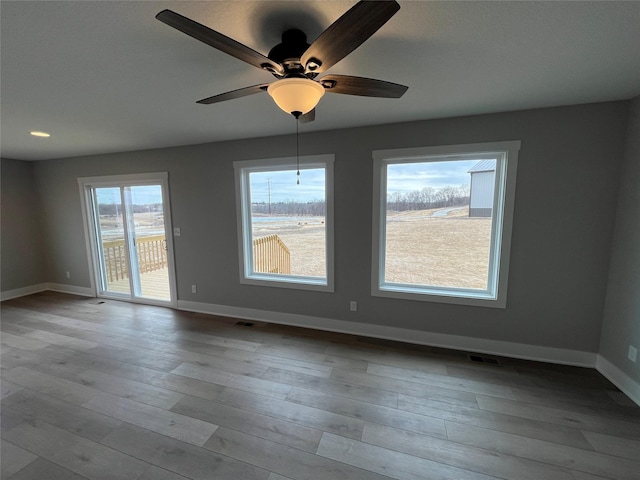 unfurnished room with light wood-style flooring, visible vents, and baseboards