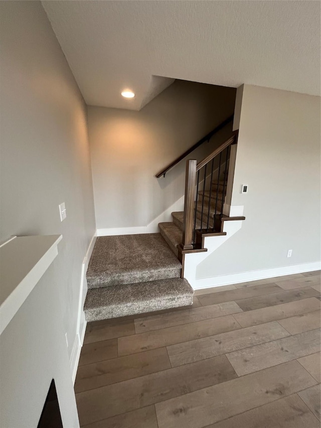 stairs with a textured ceiling, baseboards, wood finished floors, and recessed lighting