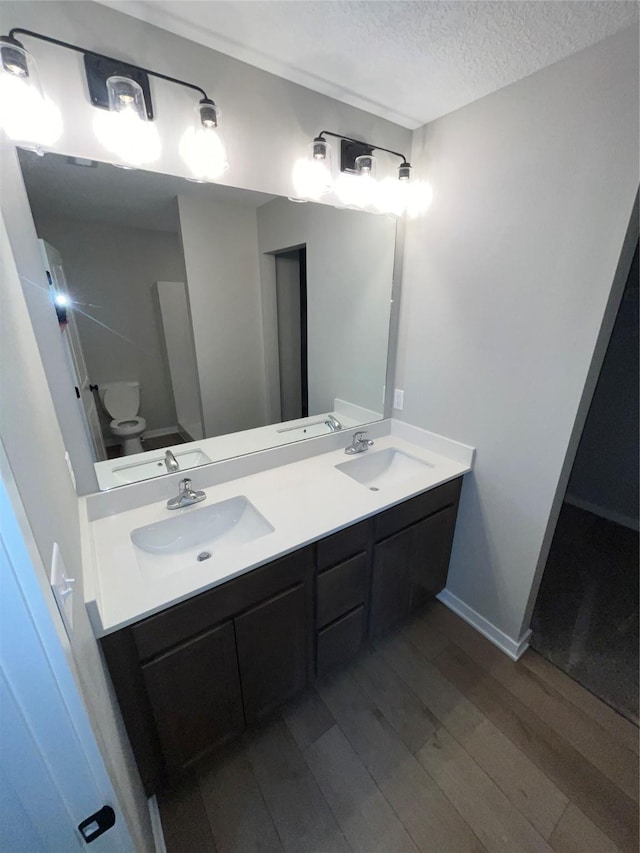 bathroom featuring a textured ceiling, double vanity, wood finished floors, and a sink