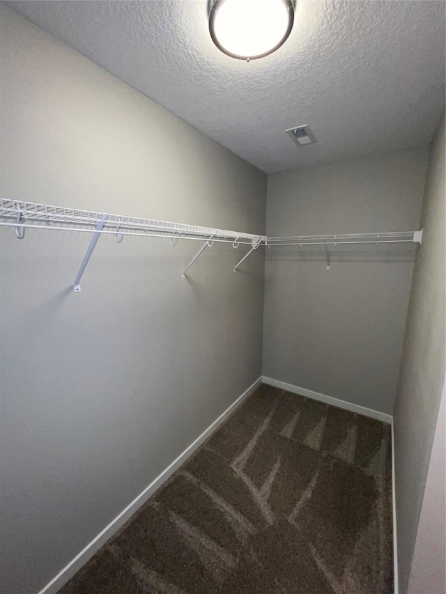 spacious closet featuring visible vents and dark colored carpet