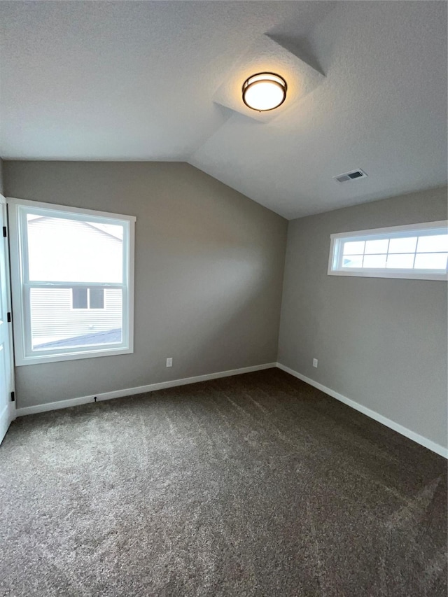 bonus room featuring vaulted ceiling, dark carpet, visible vents, and baseboards