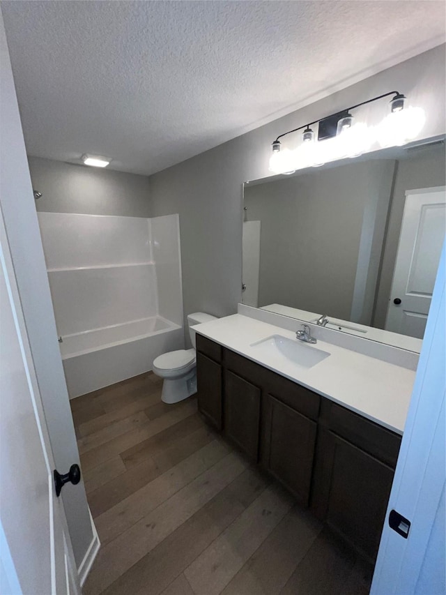 bathroom featuring shower / bathing tub combination, toilet, a textured ceiling, vanity, and wood finished floors