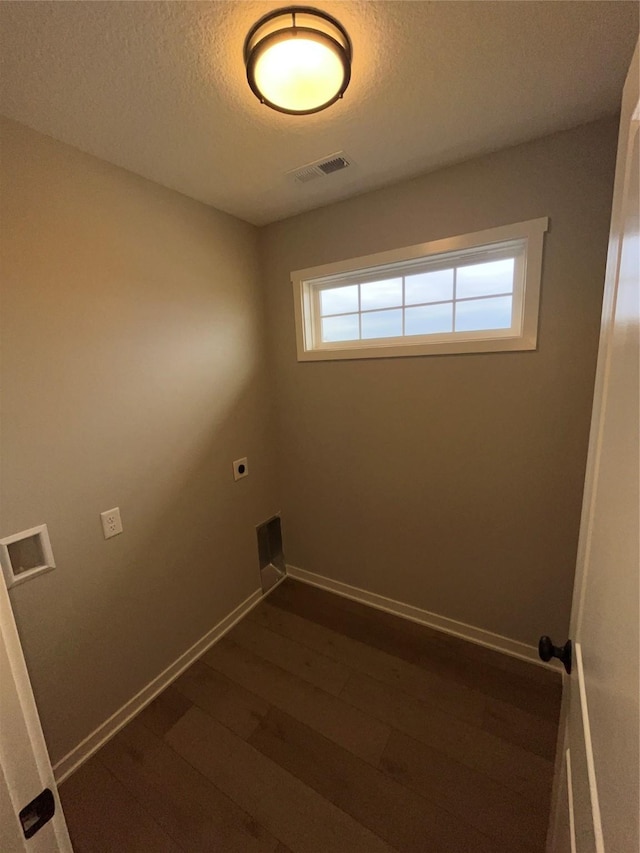 laundry area with a textured ceiling, laundry area, dark wood-type flooring, visible vents, and baseboards