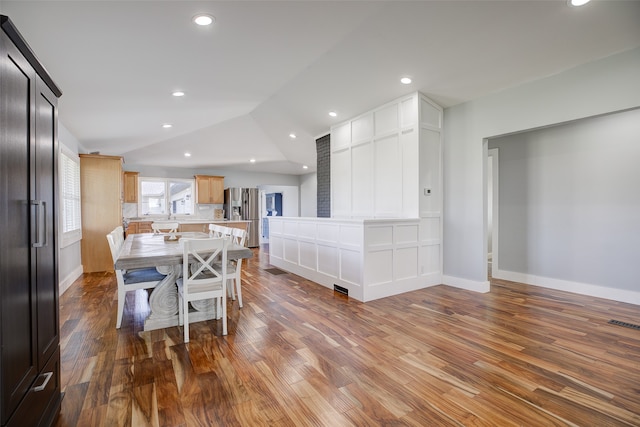 kitchen featuring a kitchen island, a kitchen bar, decorative backsplash, hardwood / wood-style flooring, and lofted ceiling