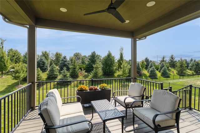 wooden deck with an outdoor living space, a lawn, and ceiling fan