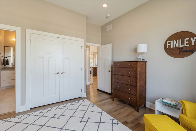 bedroom featuring connected bathroom, a closet, light hardwood / wood-style flooring, and high vaulted ceiling