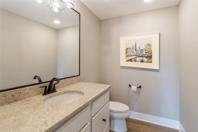 bathroom with wood-type flooring, vanity, and toilet