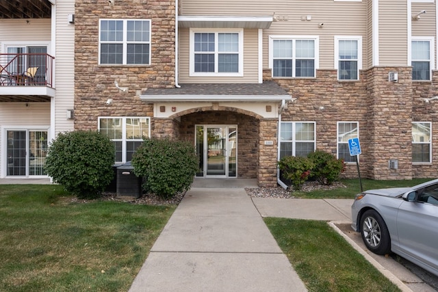 doorway to property with stone siding, a lawn, and central air condition unit