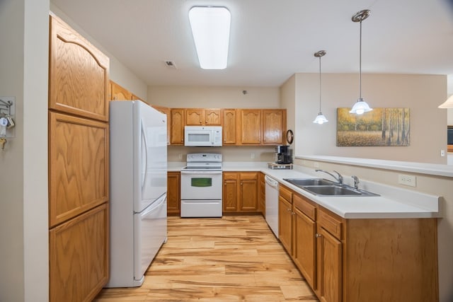 kitchen with light countertops, light wood-style flooring, a sink, white appliances, and a peninsula