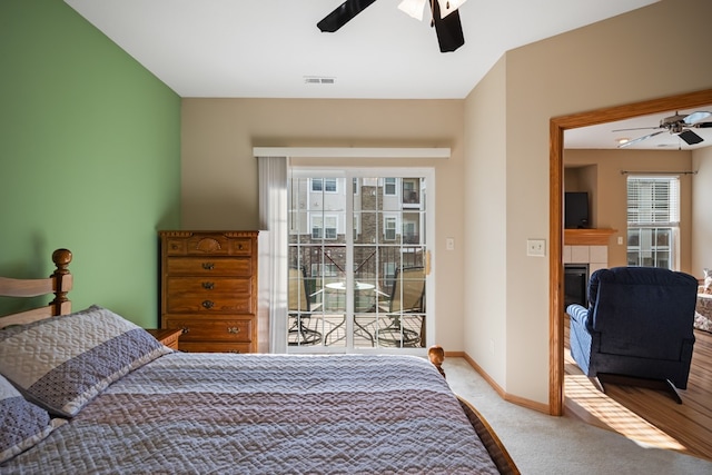 bedroom with a tile fireplace, carpet flooring, a ceiling fan, visible vents, and baseboards