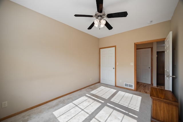 unfurnished bedroom with a ceiling fan, light colored carpet, visible vents, and baseboards