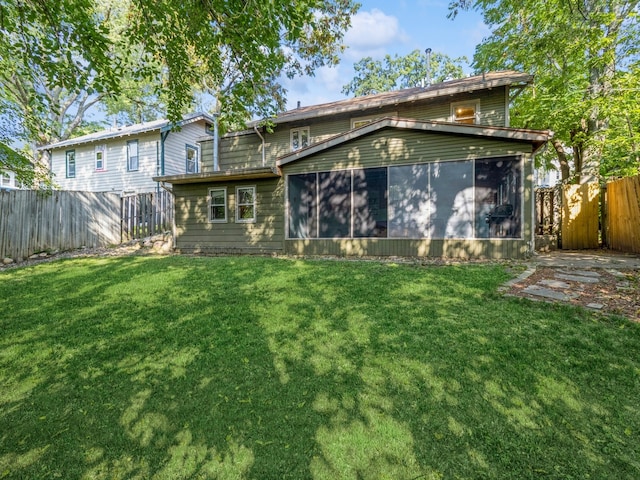 rear view of house featuring a sunroom and a lawn