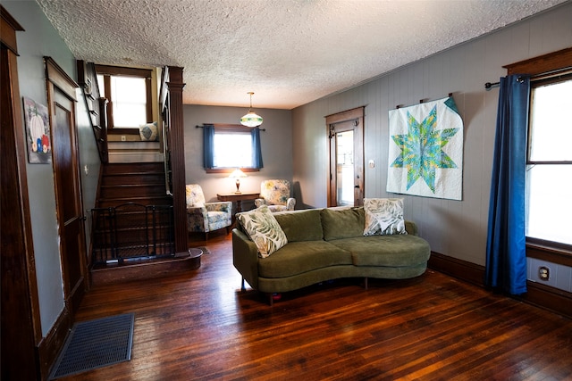 living room with a textured ceiling and dark hardwood / wood-style floors