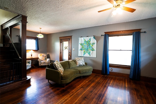 living room featuring ceiling fan, dark hardwood / wood-style flooring, and a textured ceiling