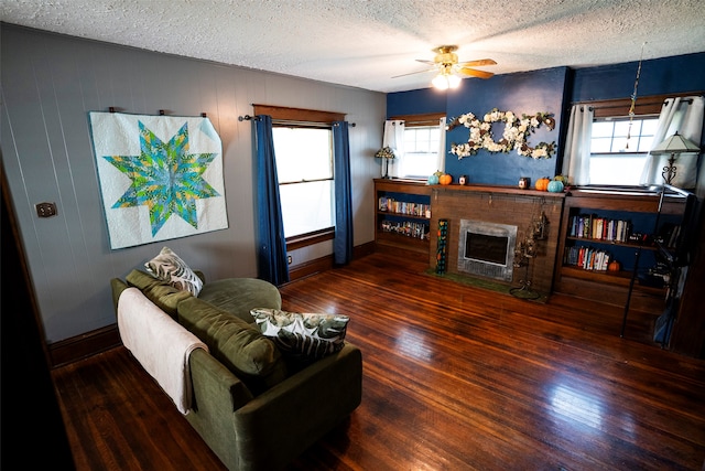 living room featuring dark hardwood / wood-style flooring, a brick fireplace, ceiling fan, and a healthy amount of sunlight