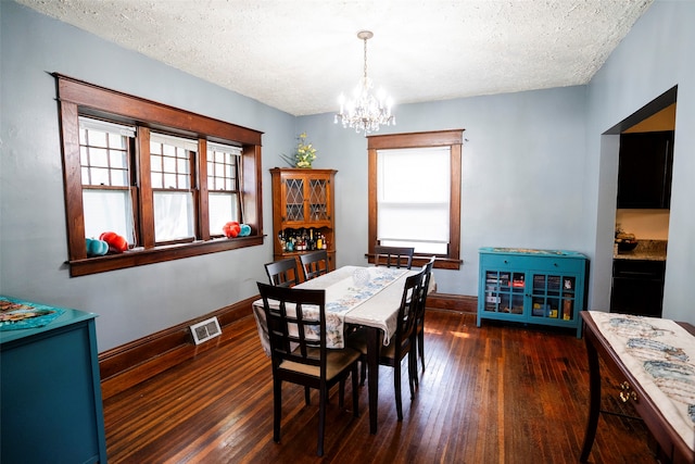 dining room featuring a textured ceiling, a chandelier, and dark hardwood / wood-style flooring