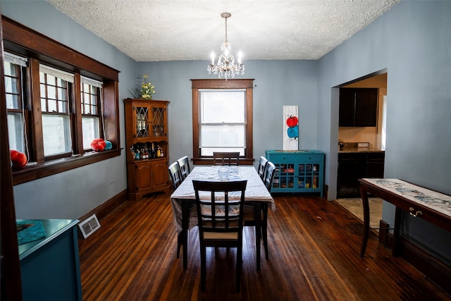 dining room with dark hardwood / wood-style flooring, a notable chandelier, and a textured ceiling