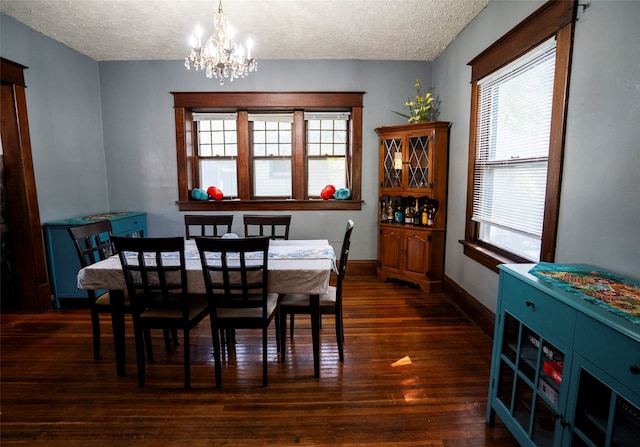 dining space featuring a textured ceiling, dark wood-type flooring, and an inviting chandelier