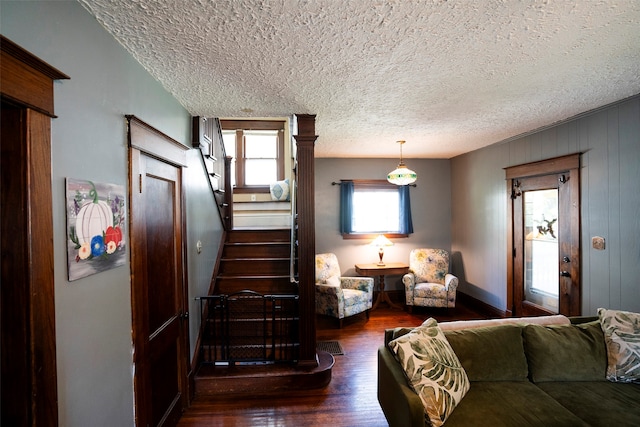 living room featuring wood walls, dark hardwood / wood-style floors, and a textured ceiling