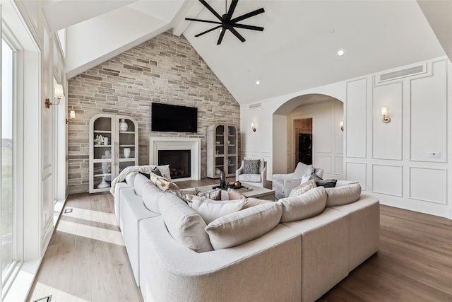 living room featuring ceiling fan, beamed ceiling, high vaulted ceiling, light hardwood / wood-style floors, and a fireplace