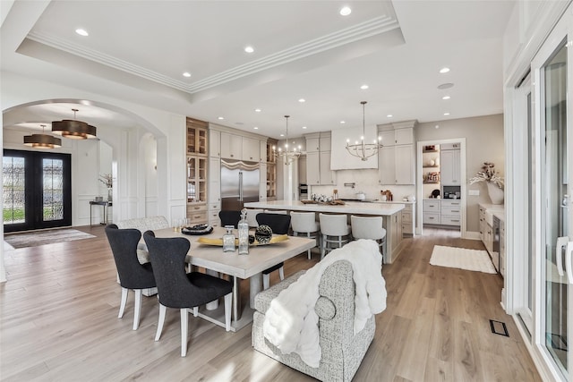 18252 Valleyview Cir, Clive, IA 50325 - dining area featuring arched walkways, a tray ceiling, a chandelier, light wood-style flooring, and recessed lighting