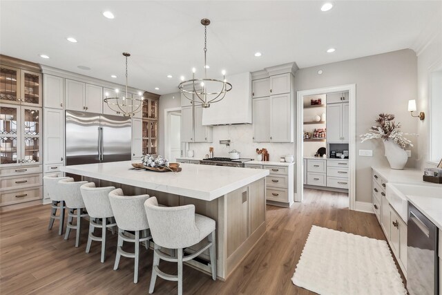 18252 Valleyview Cir, Clive, IA 50325 - kitchen featuring appliances with stainless steel finishes, a chandelier, a kitchen island, wood finished floors, and a kitchen bar