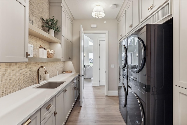 18252 Valleyview Cir, Clive, IA 50325 - washroom featuring light wood-style flooring, cabinet space, stacked washer / drying machine, and baseboards